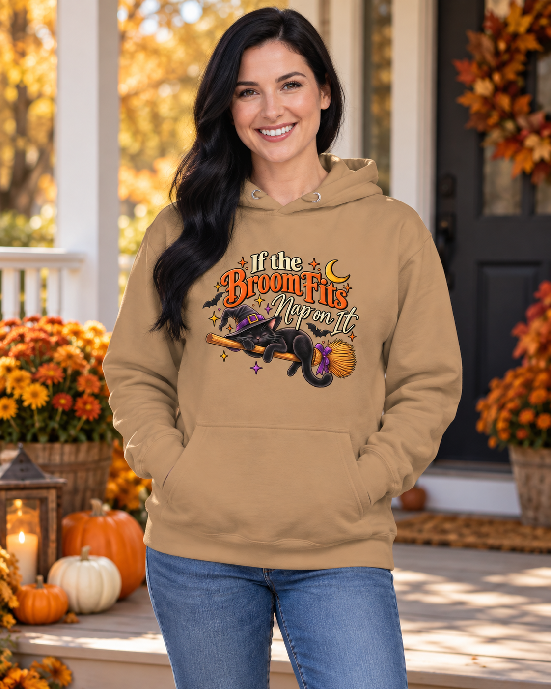 Woman wearing a latte “If the Broom Fits, Nap on It” cat hoodie on a fall porch.